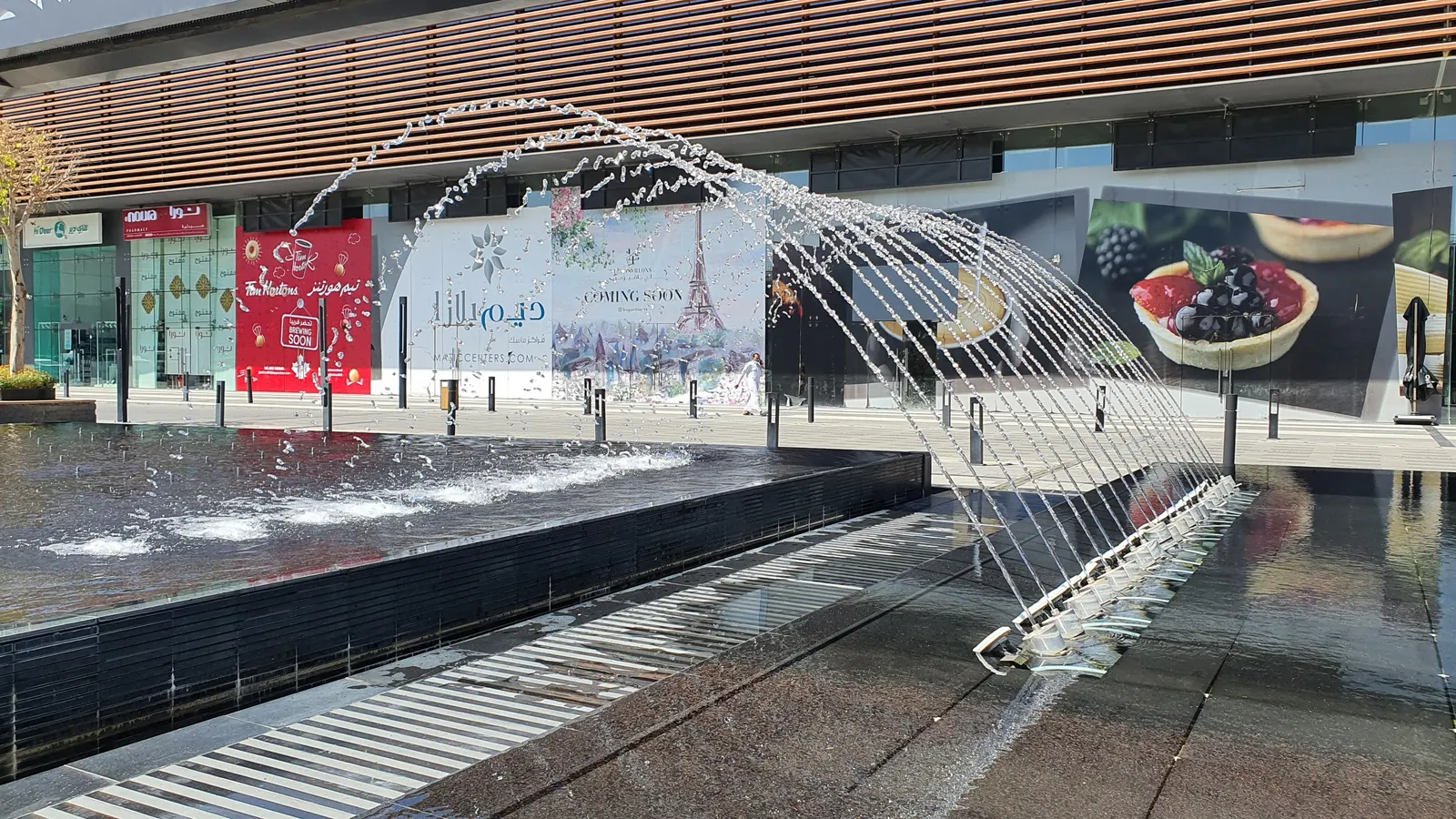 Arcing water jets over the fountain pool by day