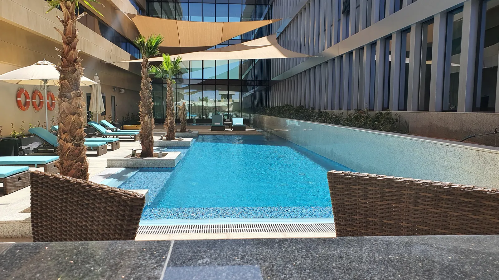Palm-lined pool framed by the hotel buildings