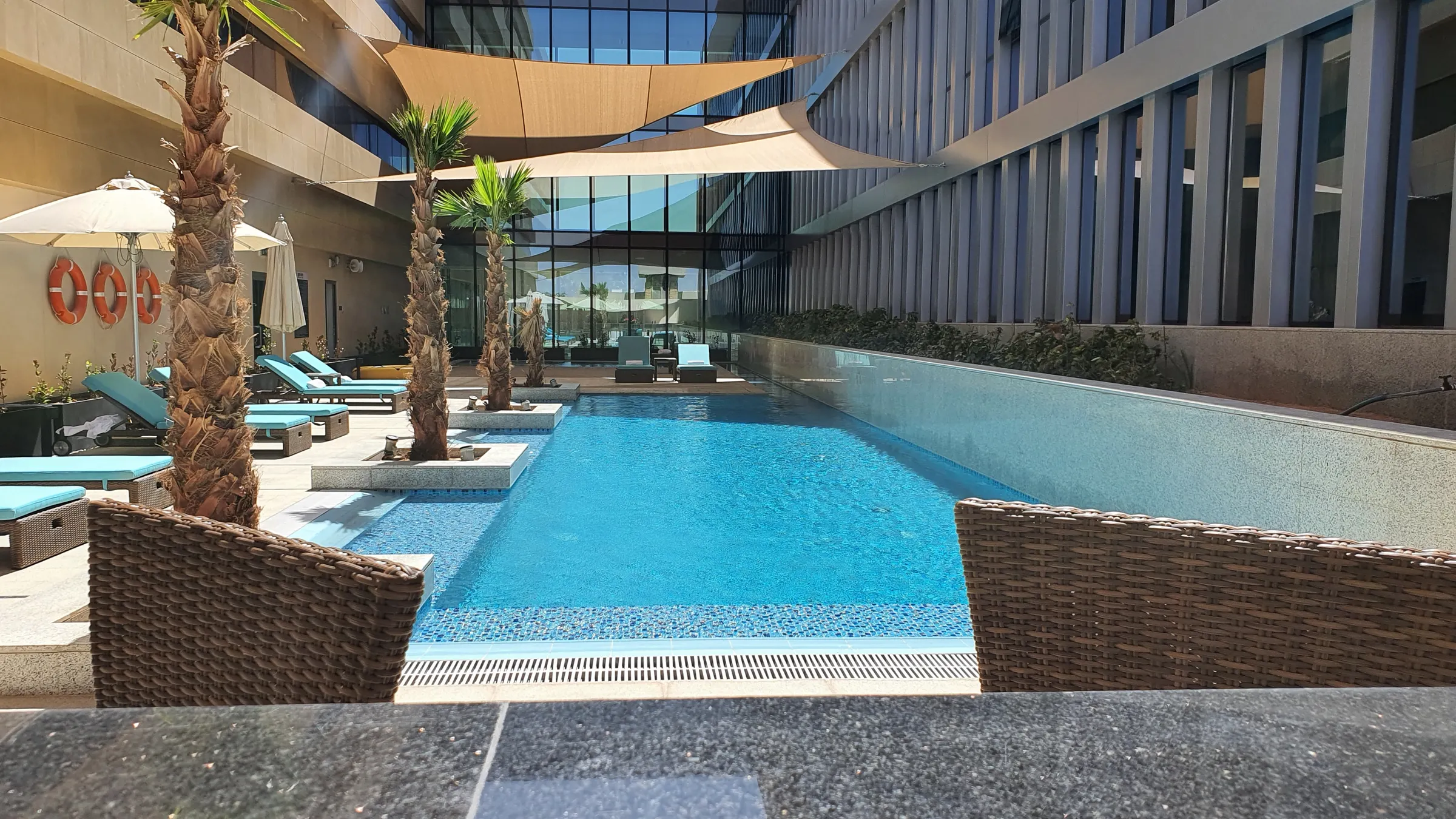 Palm-lined pool framed by the hotel buildings