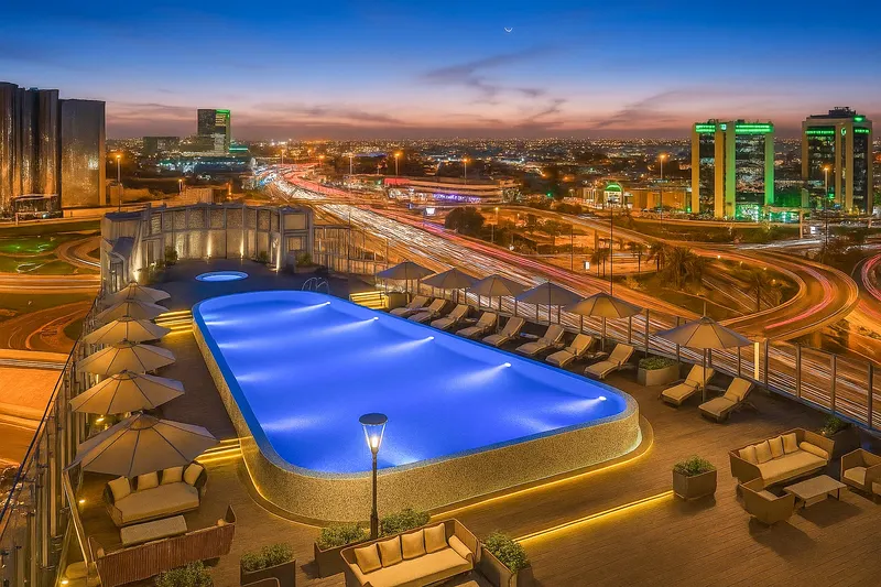 Rooftop hotel pool lit at dusk above the city