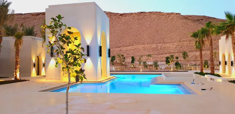 Villa pool lit against a desert escarpment